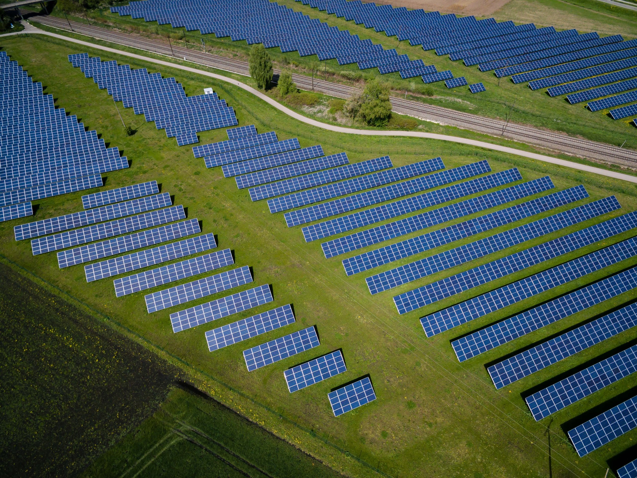 Vue aérienne de panneaux solaires sur une prairie et une route Crédits photo : Andreas Gücklhorn sur Unsplash